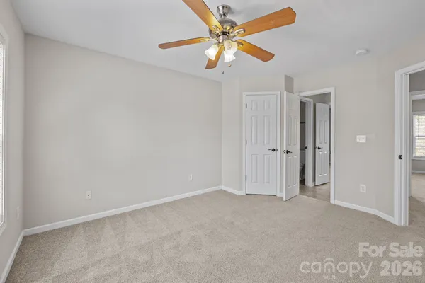 an empty room with closet and a ceiling fan