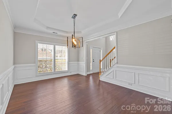 a view of an empty room with wooden floor entryway and a window