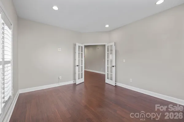 an empty room with wooden floor & windows