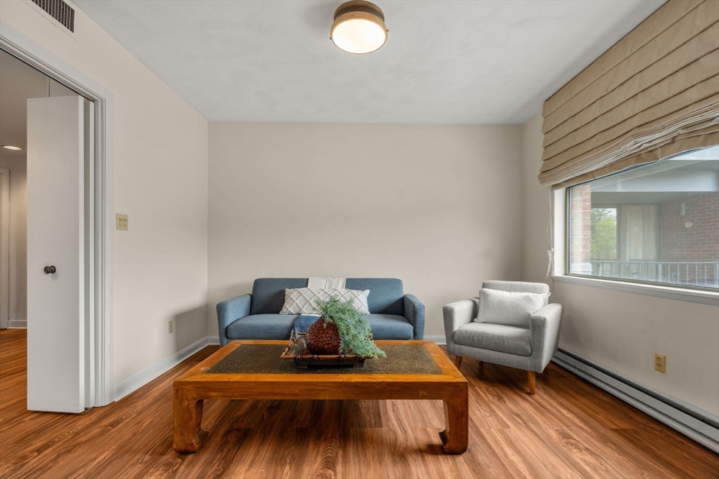 75 Grove Street, Unit 227 Wellesley, MA 02482 - Photo 10 of 29 a bedroom with a bed and wooden floor