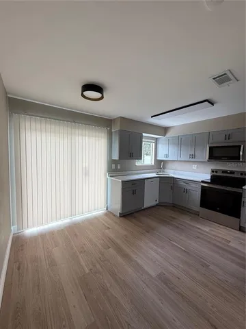 a large kitchen with a large counter top a sink stainless steel appliances and cabinets