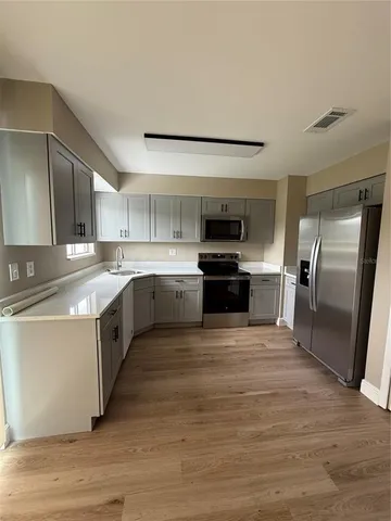 a kitchen with stainless steel appliances granite countertop a stove top oven a sink and a refrigerator