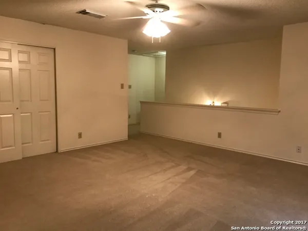 a view of an empty room with a chandelier fan