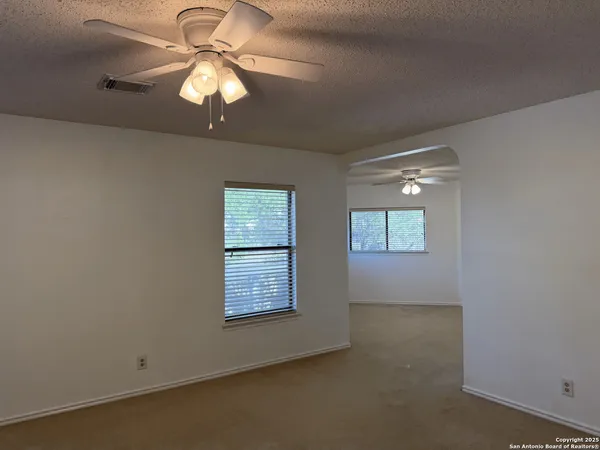 an empty room with windows and fan