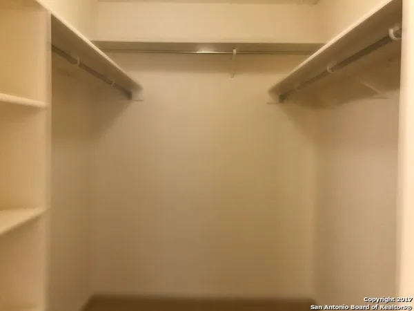 an empty room with closet and a chandelier fan