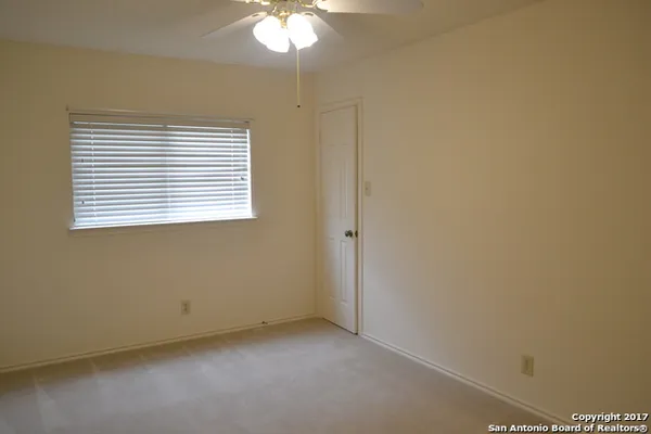 an empty room with a window and a fan