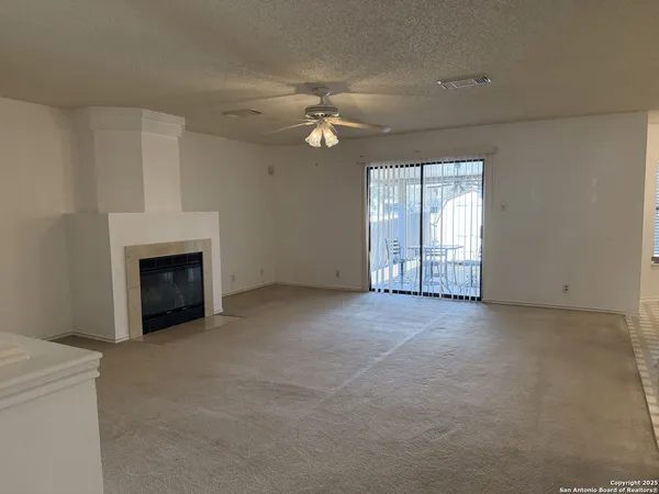 an empty room with chandelier fan and windows