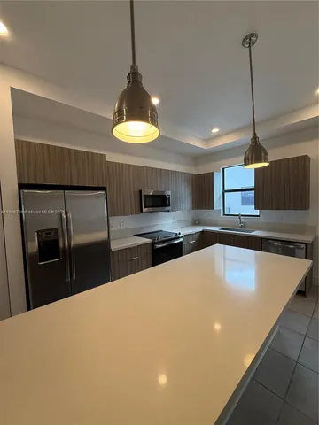 a kitchen with stainless steel appliances a stove a refrigerator a sink a stove with wooden floor