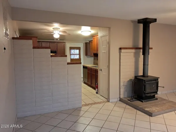 a view of a refrigerator in kitchen and an empty room in wooden floor