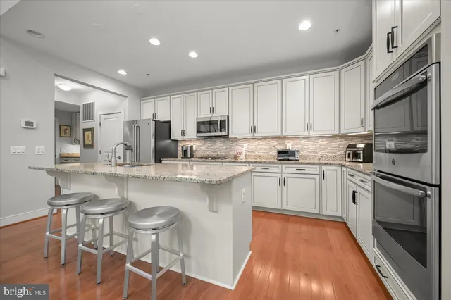 a kitchen with kitchen island granite countertop a sink cabinets and wooden floor