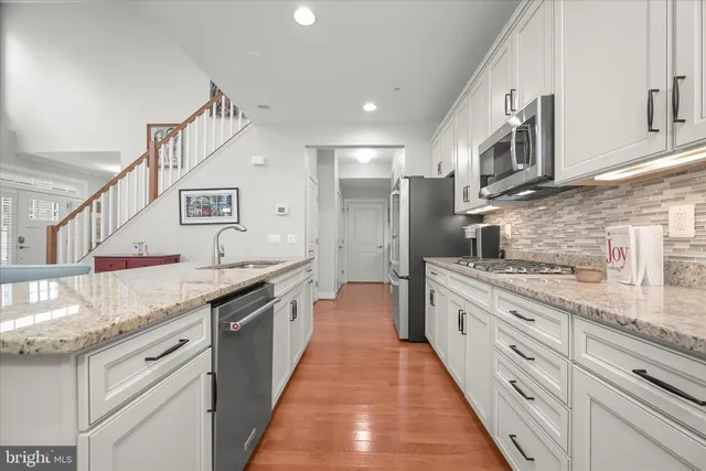 a large kitchen with stainless steel appliances granite countertop a lot of counter space and a sink