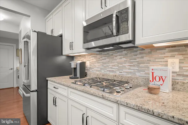 a kitchen with granite countertop stove top oven microwave and refrigerator
