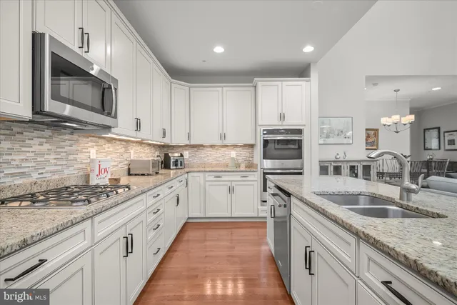 a kitchen with granite countertop a sink stainless steel appliances and cabinets