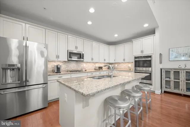 a kitchen with stainless steel appliances granite countertop a refrigerator a stove a sink and a microwave