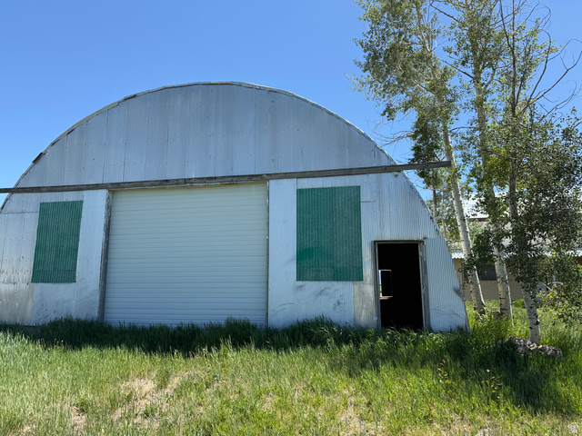 2002 Lund Road Bancroft, ID 83217 - Photo 24 of 28 Quonset hut structure featuring corrugated metal siding, a large white roll-up door, and a standard entry door