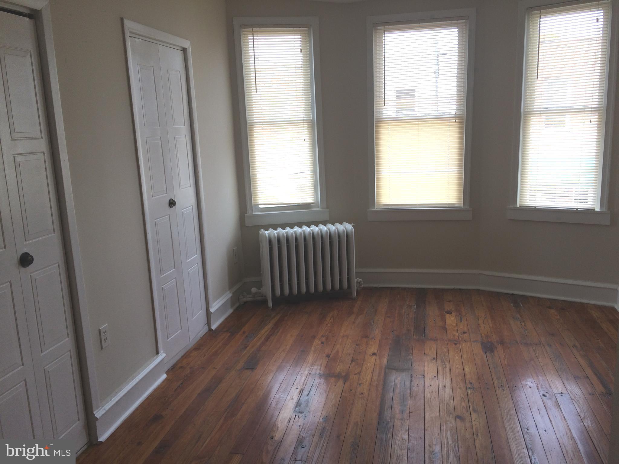 2025 South 3rd Street, Unit 2 Philadelphia, PA 19148 - Photo 3 of 8 a view of an empty room with wooden floor and a window