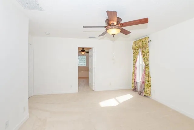 a view of a room with a ceiling fan and window