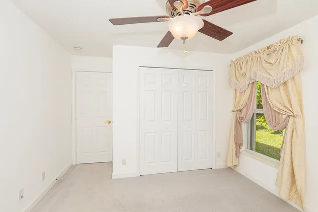 an empty room with a window and a ceiling fan