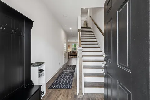 a view of staircase with white walls and a black white door