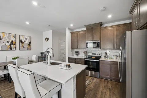 a kitchen with stainless steel appliances a stove a sink a microwave a refrigerator and cabinets