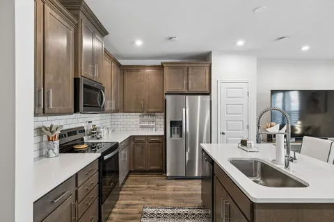 a kitchen that has a sink cabinets and stainless steel appliances