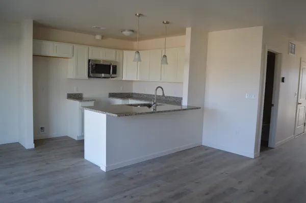 a kitchen with stainless steel appliances granite countertop a sink a microwave a refrigerator and white cabinets