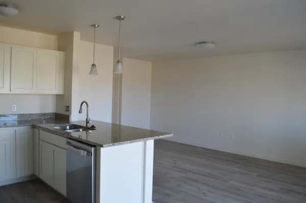 a kitchen with granite countertop a sink cabinets and wooden floor