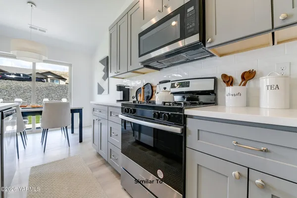 a kitchen with stainless steel appliances granite countertop a stove a sink and a microwave