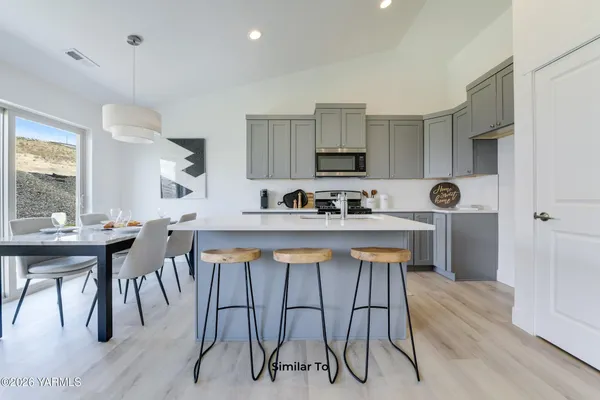 a kitchen with stainless steel appliances a table chairs refrigerator and microwave