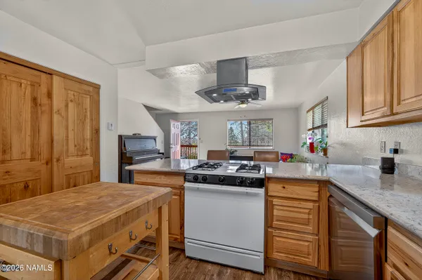 a kitchen with stainless steel appliances granite countertop a sink a stove and a wooden floors