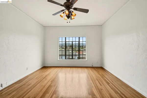 a view of an empty room with wooden floor and a window