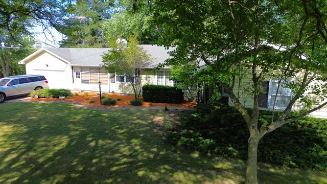 a backyard of a house with table and chairs plants and large tree
