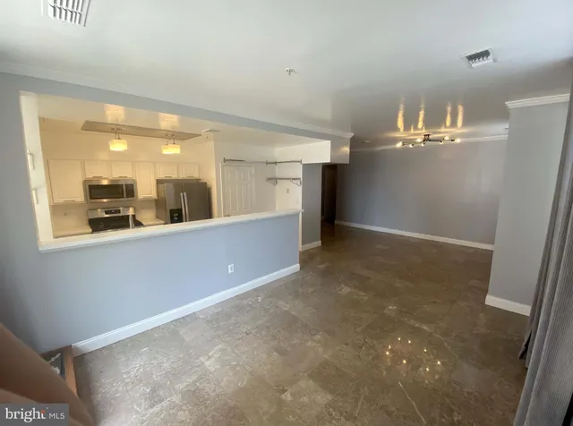 en empty room with kitchen and chandelier
