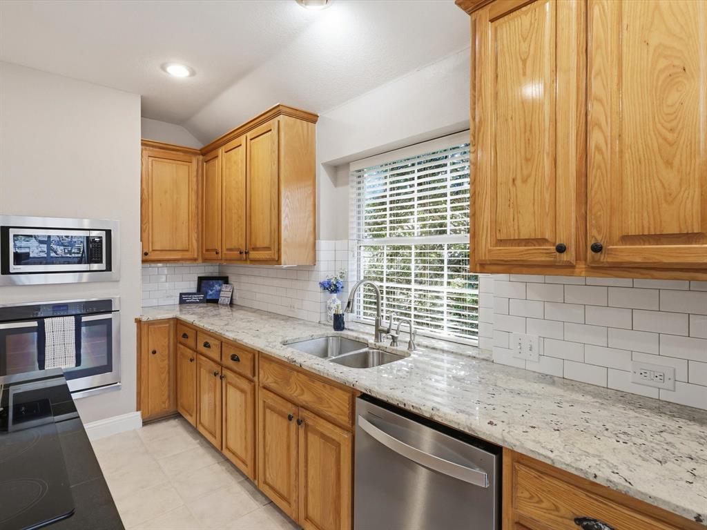 2211 Post Oak Circle Corinth, TX 76210 - Photo 13 of 40 a kitchen with stainless steel appliances granite countertop a sink a stove and a wooden cabinets