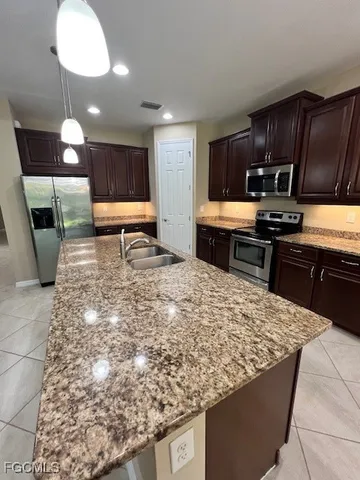 a kitchen with kitchen island granite countertop a sink counter top space appliances and cabinets