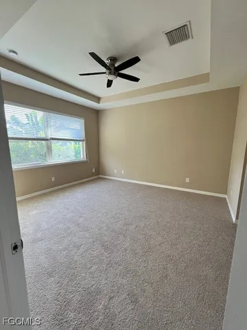 an empty room with a ceiling fan and window