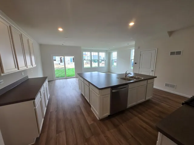a large kitchen with kitchen island wooden floors and stainless steel appliances