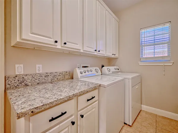 a utility room with granite countertop cabinets washer and dryer