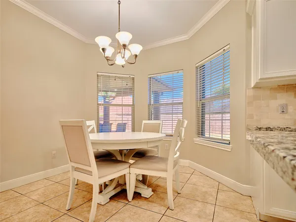 a dining room with chandelier and wooden floor