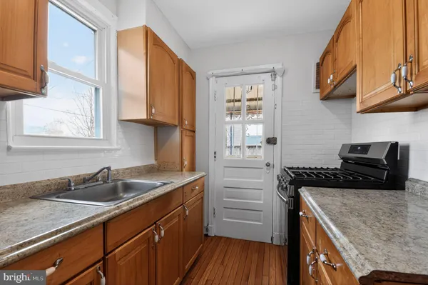 a kitchen with granite countertop a sink a stove and wooden cabinets