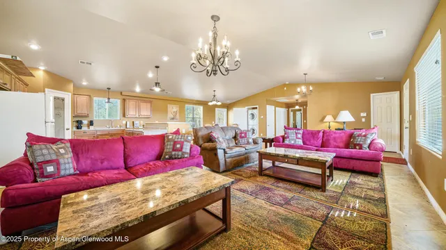 a living room with furniture kitchen view and a chandelier