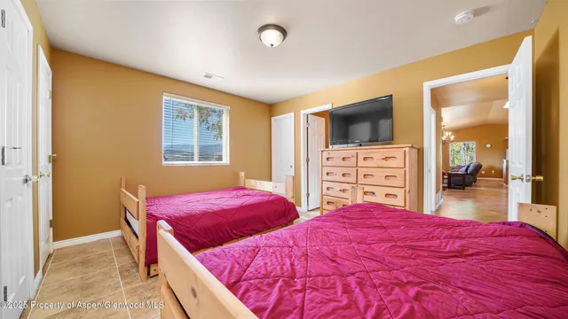 a bedroom with two bed and a flat tv screen on dresser