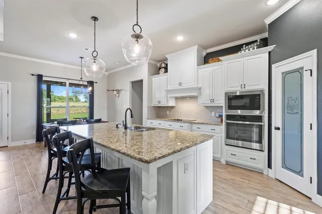 a kitchen with granite countertop a table chairs stainless steel appliances and cabinets