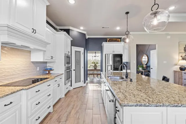 a large kitchen with stainless steel appliances granite countertop a lot of counter space and wooden floors
