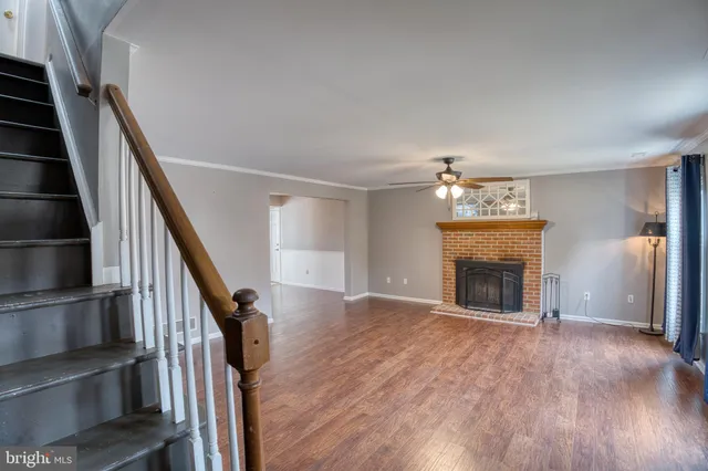a view of an empty room with wooden floor fireplace and a window