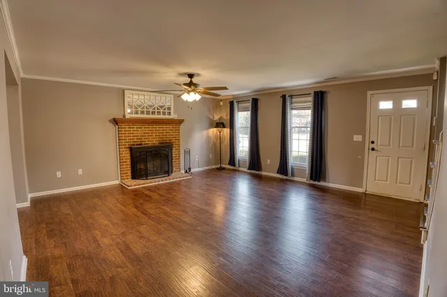 an empty room with wooden floor fireplace and windows