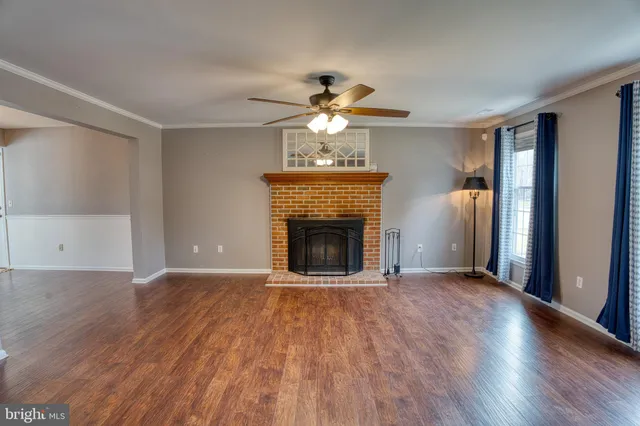 a view of a livingroom with a fireplace a chandelier and wooden floor