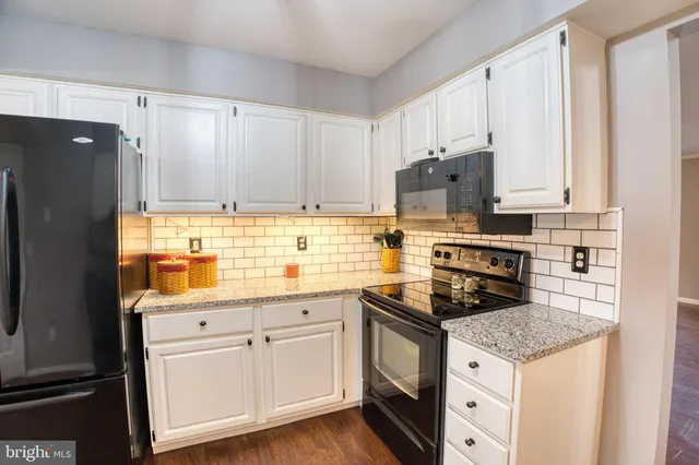 a kitchen with granite countertop a stove sink and refrigerator