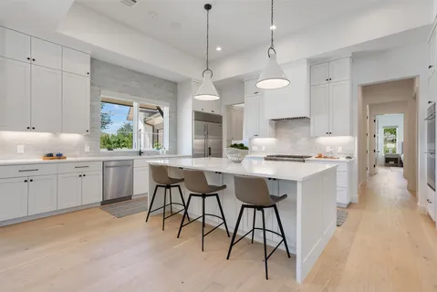 a kitchen with stainless steel appliances kitchen island granite countertop a table chairs sink and cabinets