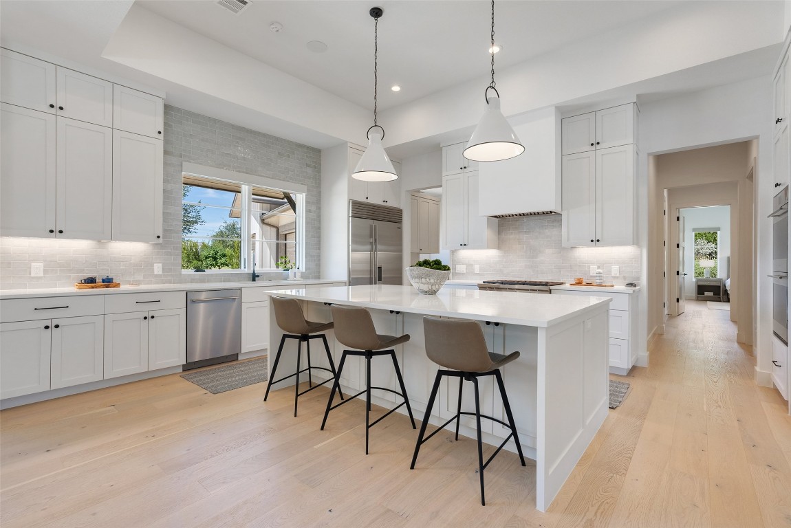15236 Grumbles Lane Austin, TX 78738 - Photo 19 of 37 a open kitchen with a refrigerator a sink dishwasher a dining table and chairs with wooden floor
